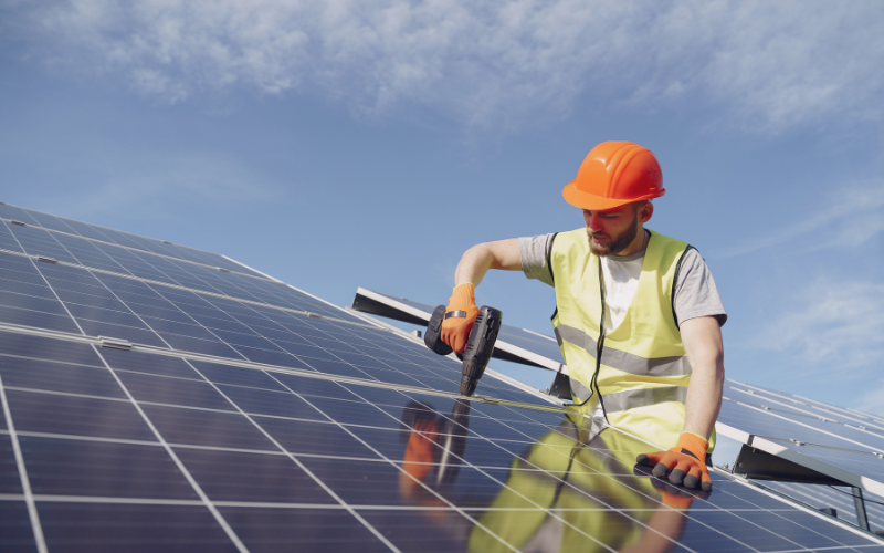 homme posant des panneaux solaires sur un toit